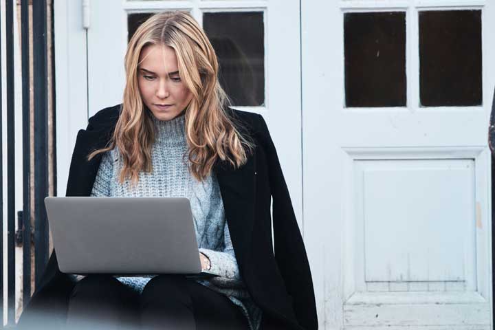 Flicka sitter på trappa med en laptop i knät