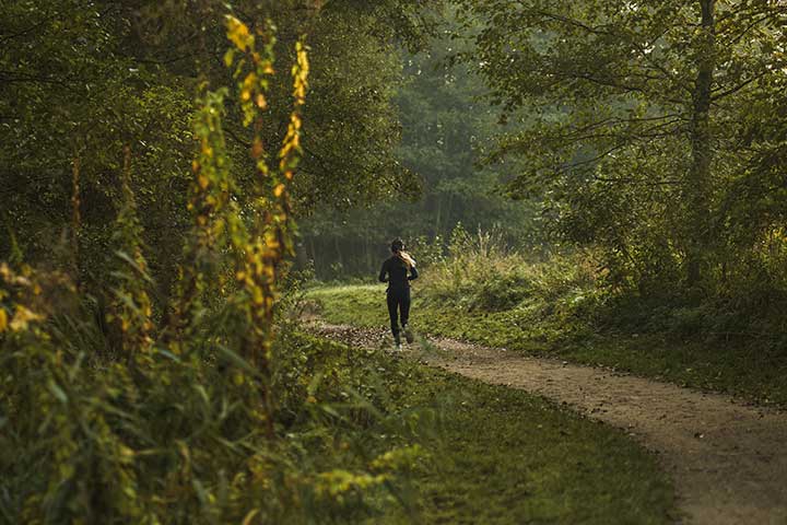 person springer i grön skog
