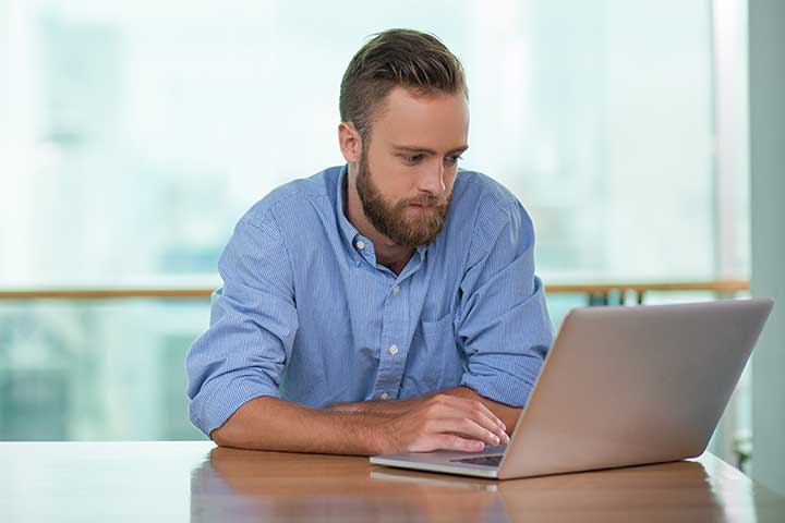 Man läser en jobbannons och förbereder sig inför intervju vid sin laptop i en ljus miljö.