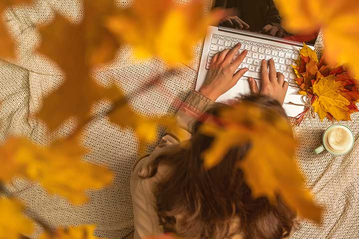 Jobbsökande vid laptop med höstlöv och kaffe